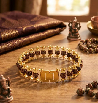 Gold plated Rudraksha bracelet on a wooden surface with decorative items.