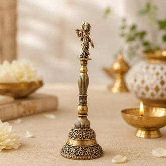 Premium handcrafted brass pooja bell featuring Lord Krishna playing the flute, designed for daily worship, temple rituals, and spiritual décor. DhamrikLife