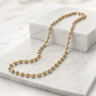 Gold-plated Tulsi Mala with 60 Tulsi beads displayed on a white marble surface