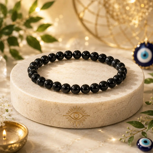 Black tourmaline beaded bracelet on a round stone platform with decorative elements in the background