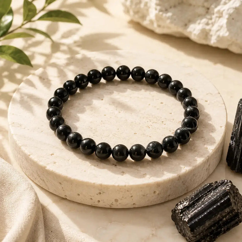 Blacktourmaline beaded bracelet on a round stone surface with natural elements.