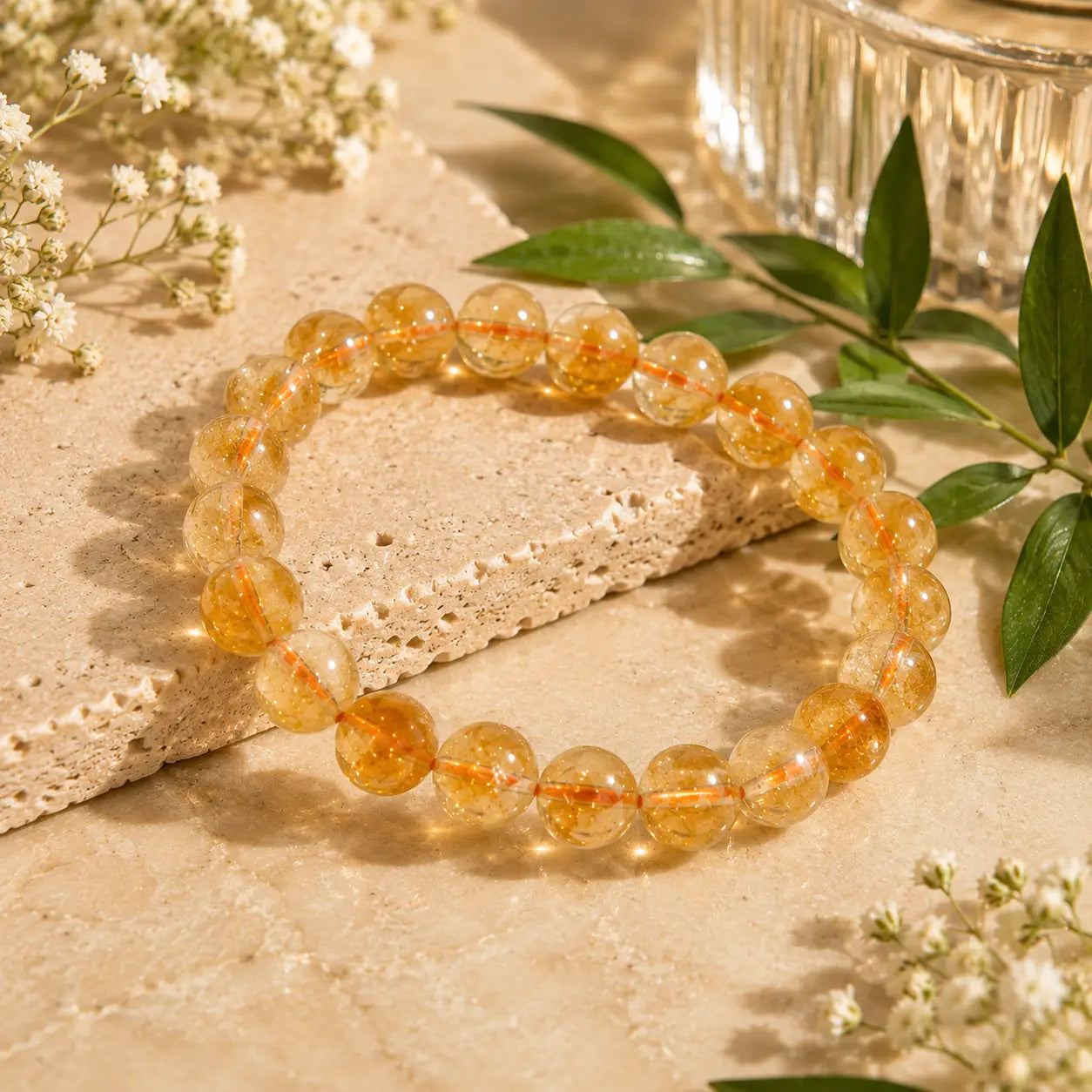 Citrine bracelet on a textured surface with green leaves and flowers