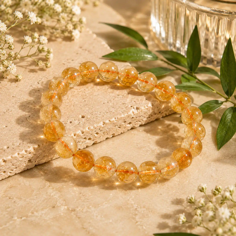 Citrine bracelet on a textured surface with green leaves and flowers