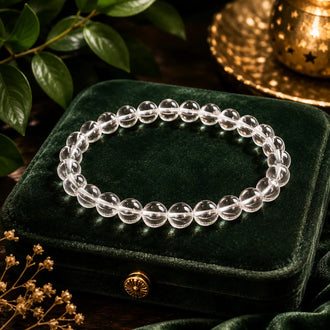 Clear quartz beaded bracelet on a green velvet box with leaves and candle in the background