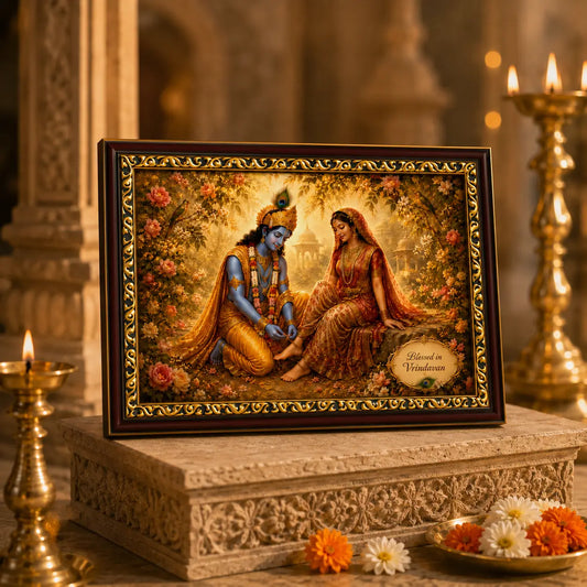 Framed artwork of Radha Krishna in a decorative setting with candles and flowers.