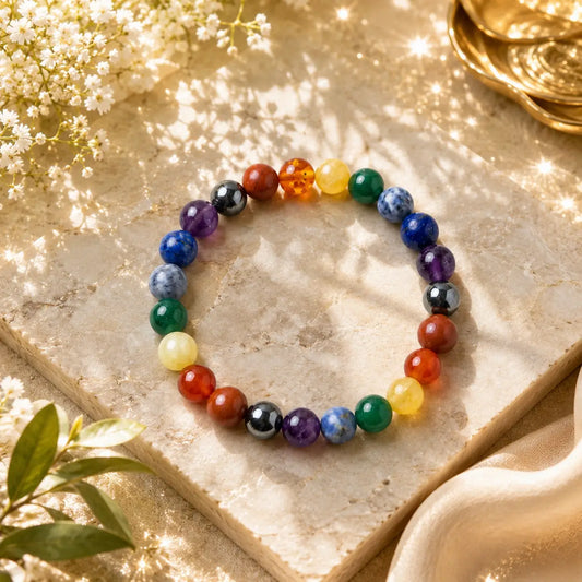 7 Chakra beaded bracelet on a textured surface with flowers and gold elements.