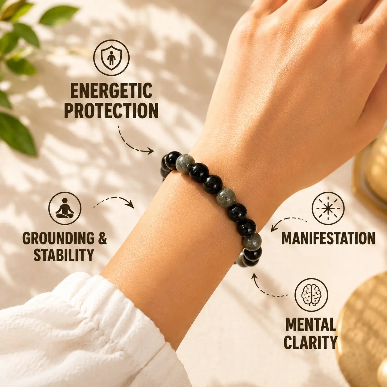 Hand wearing a black beaded bracelet with energy benefits text on a neutral background