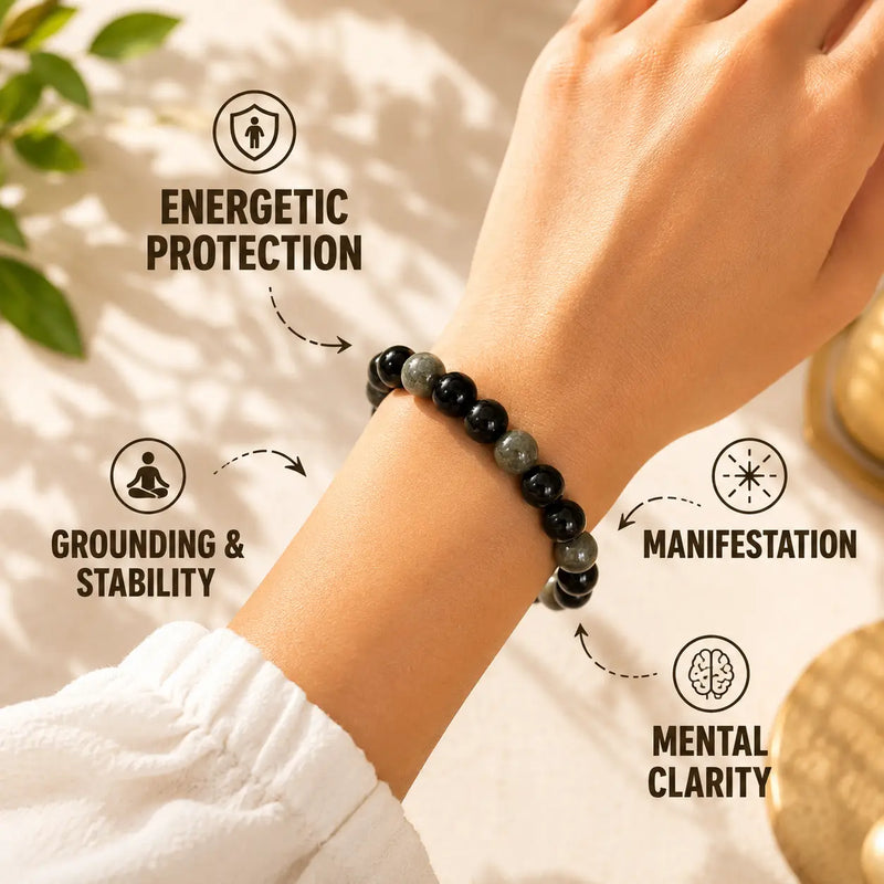 Hand wearing a black beaded bracelet with energy benefits text on a neutral background
