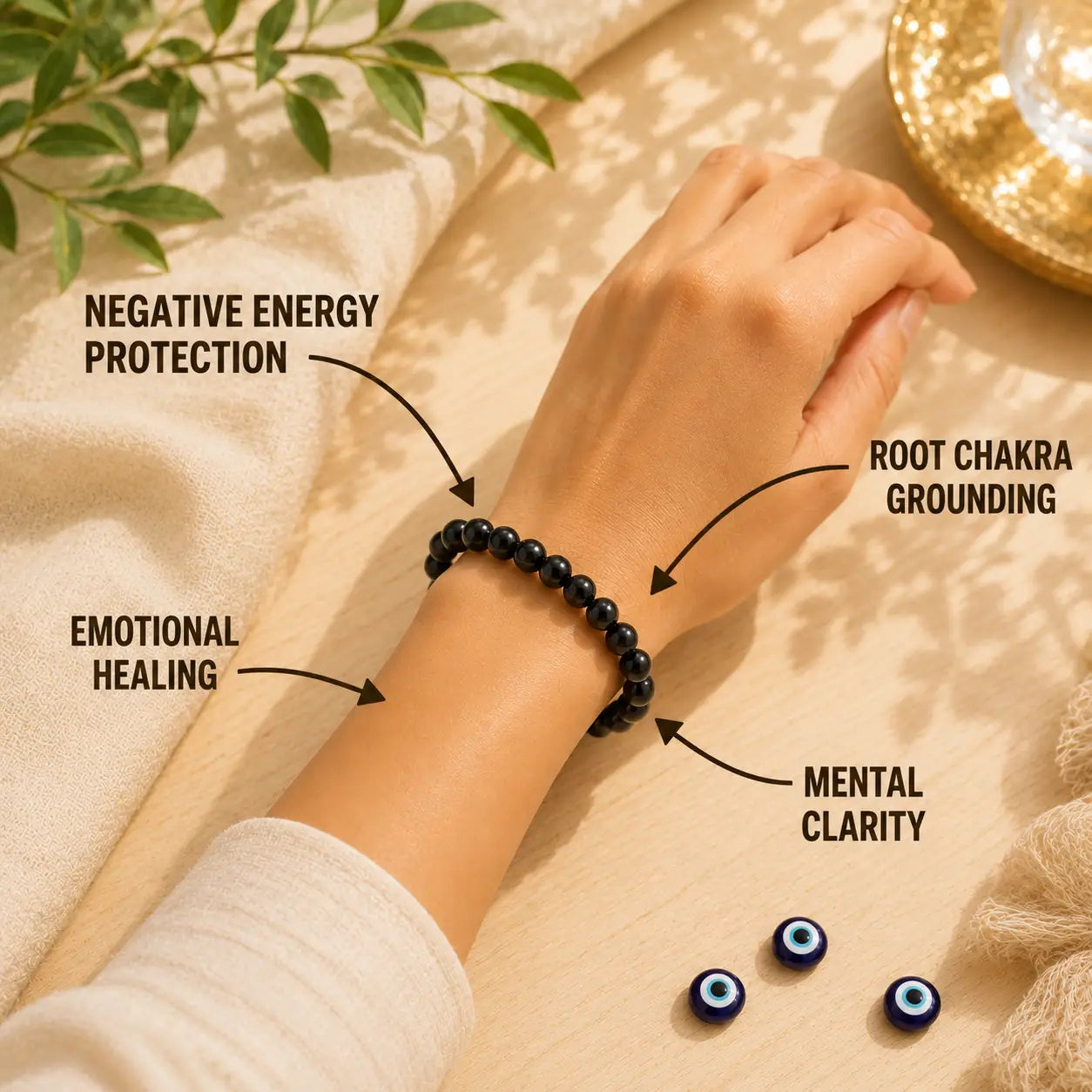Hand wearing a black tourmaline beaded bracelet with labeled benefits on a neutral background