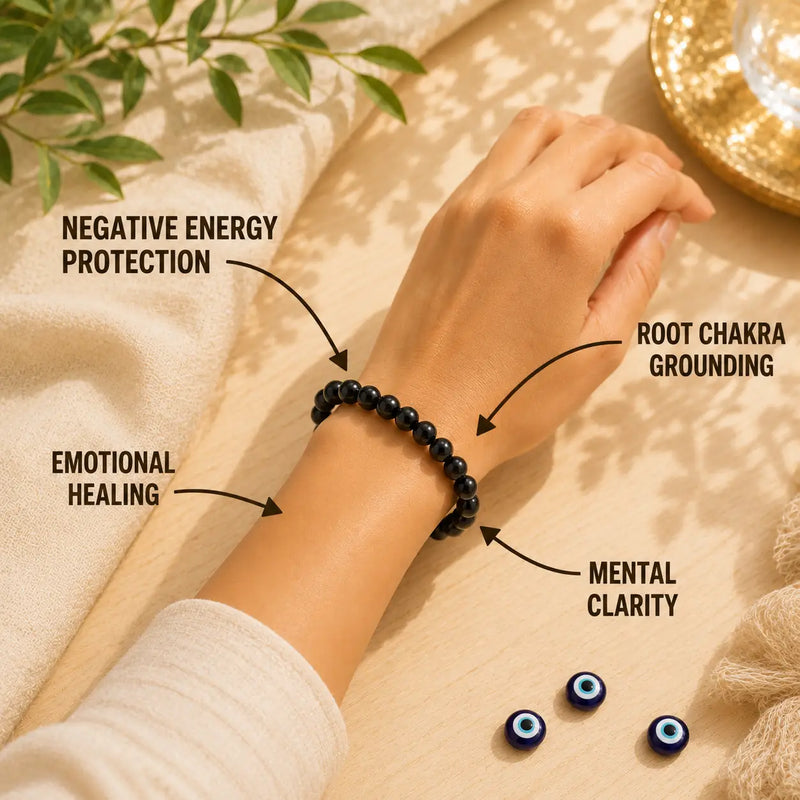 Hand wearing a black tourmaline beaded bracelet with labeled benefits on a neutral background