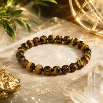 Tiger eye beaded bracelet on a stone surface with crystals and leaves