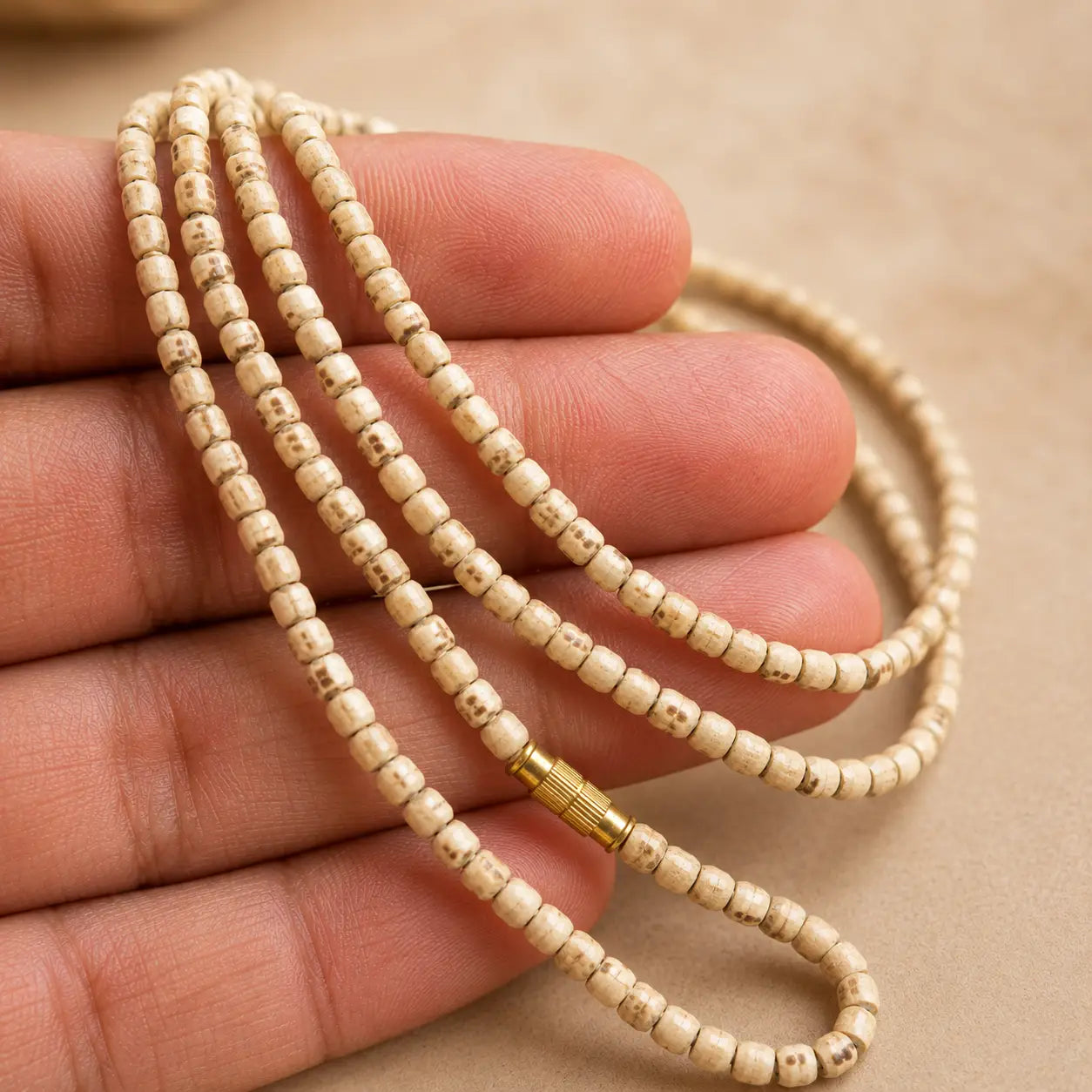 Tulsi Kanthi Mala 6m bead placed on a hand with beige background
