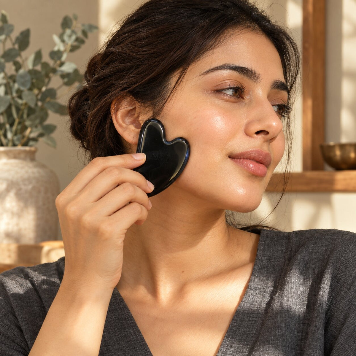 woman using black obsidian crystal Gua Sha 